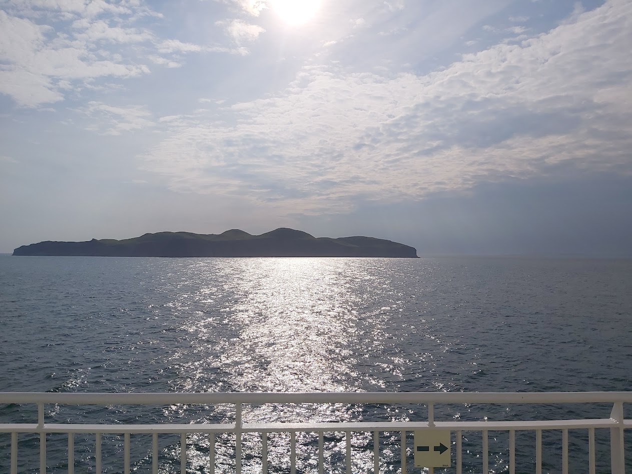 reflet du soleil sur l'eau, pont du bateau, ile au loin